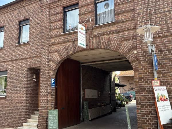 Die Toreinfahrt des Backsteinhofes mit dem Aufsteller „Der Hofladen“